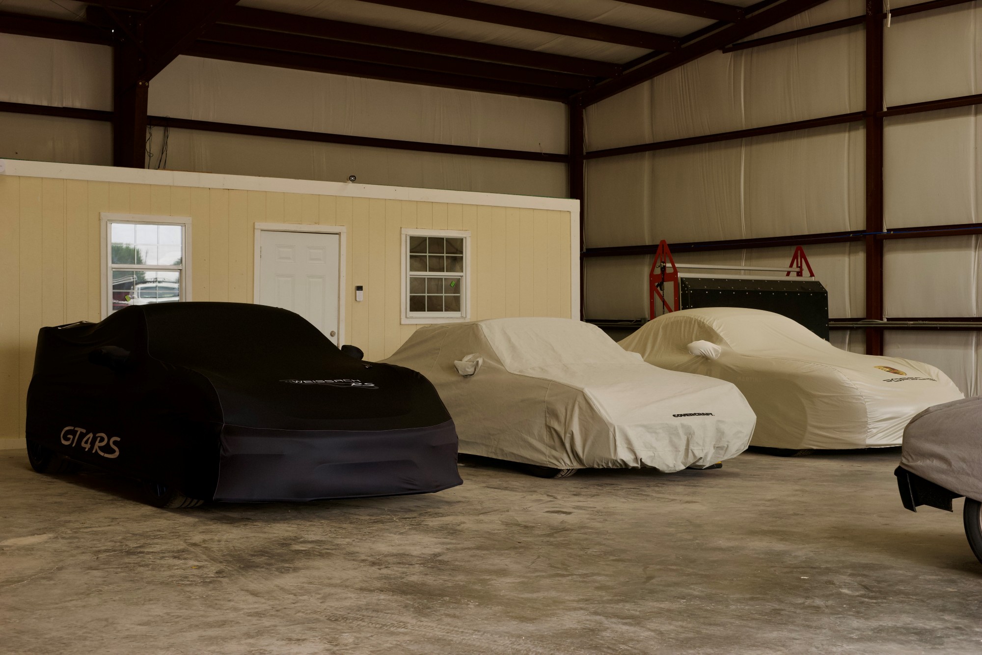 Covered vehicles parked indoors at 202 Garage